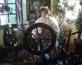 Photograph of a woman in colonial costume with spinning wheels
